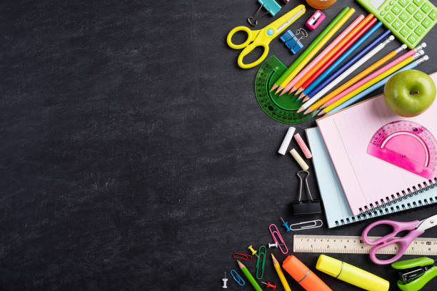 教育または学校の概念に戻る。黒板の背景に本、色鉛筆、電卓、ペンカッタークリップと緑のリンゴとカラフルな学用品のトップビュー。平らな横たわる。 - writing equipment 写真 ストックフォトと画像