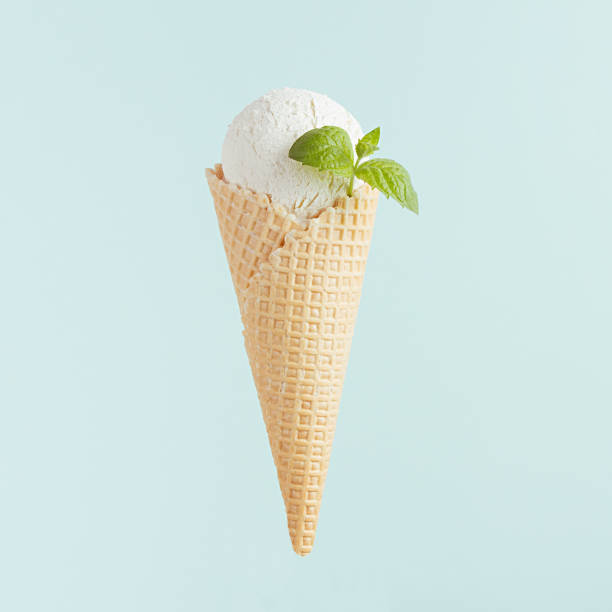 istock White ice cream cone scoop in waffle cone with mint leaf on soft light pastel green background, closeup, square. 1164091693