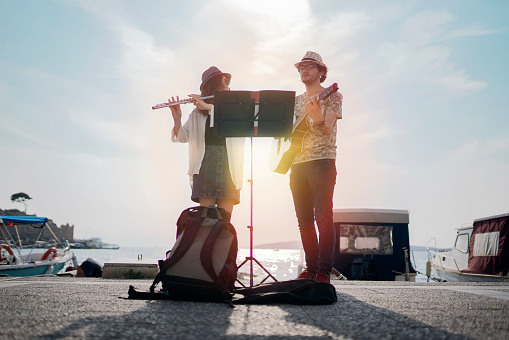 Flutist and her guitarist friend are playing on the street