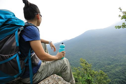 Successful woman hiker enjoy the view at mountain peak cliff edge