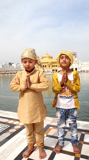 Two little innocent little boys praying to God in Golden temple, India. The Golden Temple, also known as Darbar Sahib or Sri Harmandir Sahib (