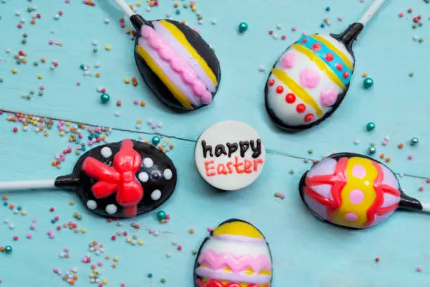 Top view of colorful chocolate candies with happy Easter text on the wooden table