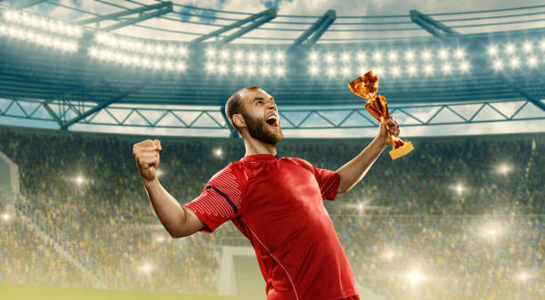 istock Soccer player celebrates victory and holds a championship cup 1164101532