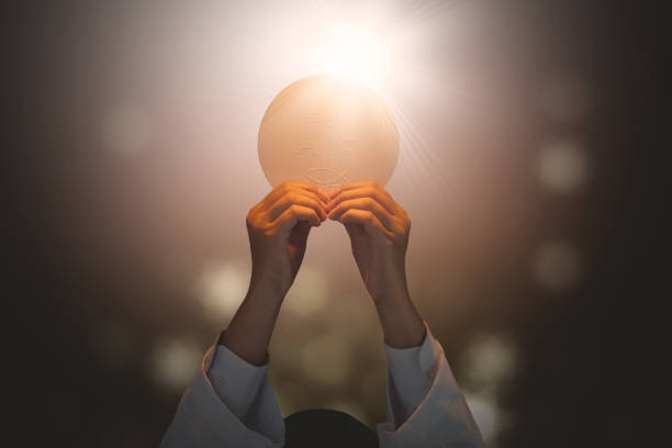 Pastor lifting a bright communion bread Close up of pastor praying to God while lifting a bright communion bread in the dark background catholicism photos stock pictures, royalty-free photos & images