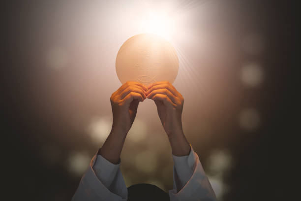 Pastor lifting a bright communion bread Close up of pastor praying to God while lifting a bright communion bread in the dark background spirituality photography close up horizontal stock pictures, royalty-free photos & images