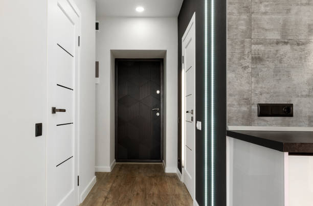 Interior of new empty apartment, long home corridor with parquet floor, white wall and doors, copy space. Entrance corridor stock photo