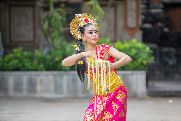 Attractive female Balinese dancer showing a dance while throwing frangipani flowers at outdoor