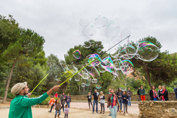 l'uomo che lancia bolle di sapone nel park guell di antonio gaudi, barcellona, spagna - antonio gaudi outdoors horizontal barcelona foto e immagini stock