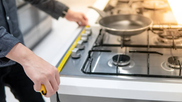 istock Male hand using tape measure on gas stove 1164115054