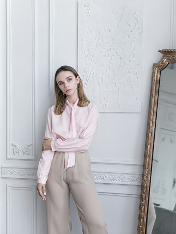 Hermosa mujer joven con blusa rosa vintage y pantalones beige en apartamento parisino photo