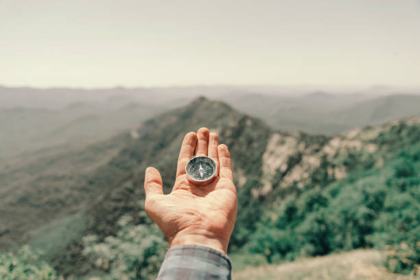 istock Compass on palm male hand high in summer mountains, pov. 1164121390