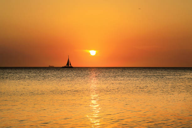 istock orange colored seascape with sailboat over sunset sky 1164123518