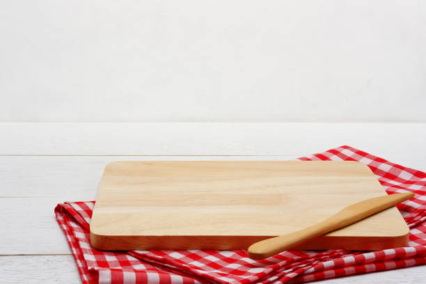 istock Empty rectangle wooden serving board with butter knife and red gingham tablecloth on white wooden table. 1164123834
