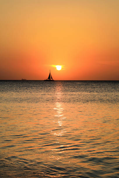 istock orange colored seascape with sailboat over sunset sky 1164124085