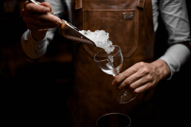 istock Bartender adds ice in cocktail glass with scoop 1164129863