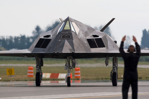 Stealth Aircraft being taxied into position with the help of a ground handler.