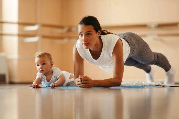 существует никаких оправданий для нее, чтобы вернуться в форму! - mother exercising baby child стоковые фото и изображения