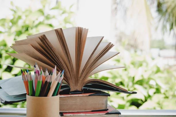 istock Open old textbook for reading in outdoor classroom daylight on stack books lecture, pencils. Ideas of education for study learning and knowledge in university or school. Classic tone, selective focus 1164140666