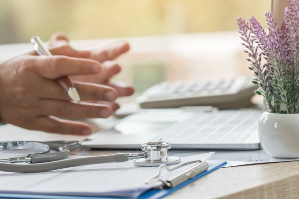 mão do doutor da medicina que explica para o paciente no quarto consultando, trabalhando no computador portátil na mesa na clínica, estetoscópio do foco na tabela do primeiro plano no hostpital. cuidados médicos e conceito médico. - hostpital - fotografias e filmes do acervo