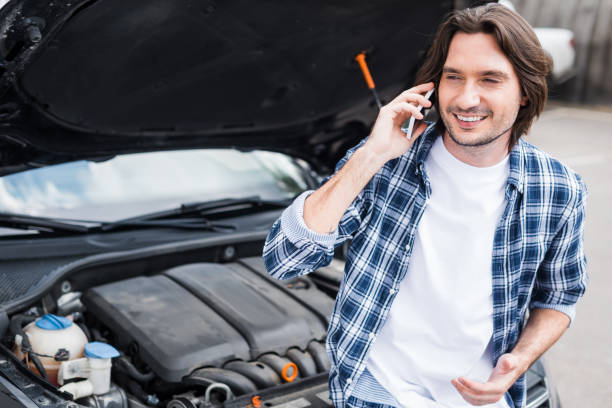 istock cheerful man in casual cothes talking on smartphone near broken auto with open trunk, car insurance concept 1164144082