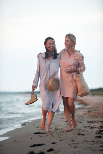 istock Two young women walking along the seacoast at sunset 1164144400