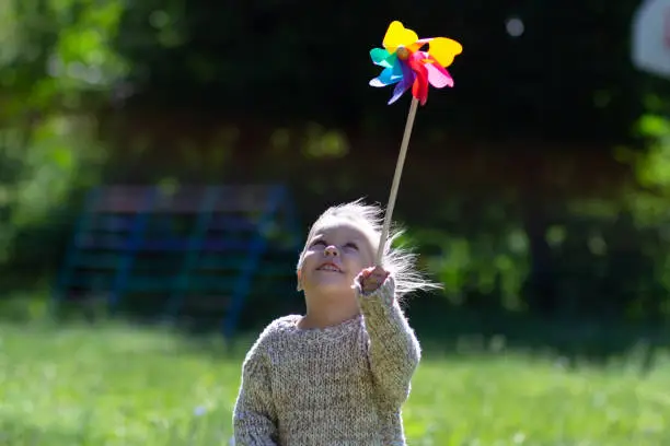 Child with Pinwheel in the summer park looking at toy