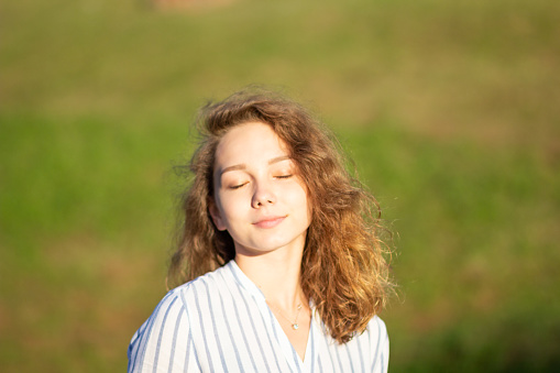 Portrait of beautiful young woman with closed eyes in summer park