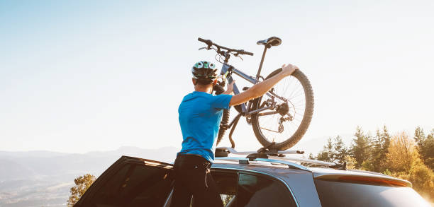 hombre ciclista de montaña tomar de su bicicleta desde el techo del coche - bicycle rack fotografías e imágenes de stock