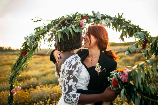 Wedding kiss Lesbian wedding ceremony. Two brides standing in a front of a wedding arch, kissing each other gay wedding kiss stock pictures, royalty-free photos & images