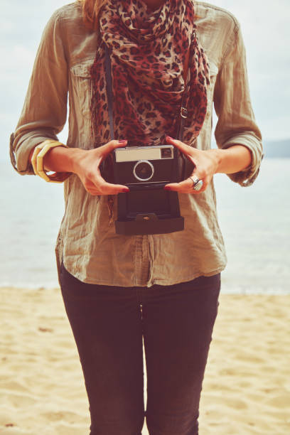 istock Attractive woman holding camera on the tropical beach. 1164145839