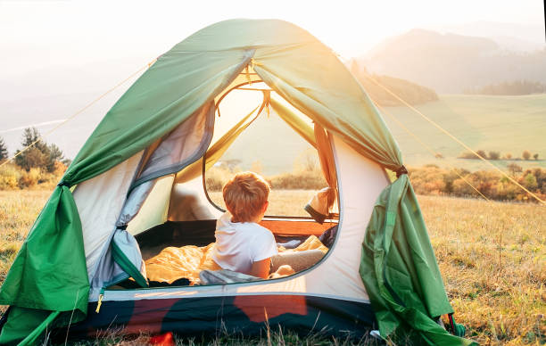 istock Boy rest in camping tent and enjoy with sunset light in mountain valley 1164146020