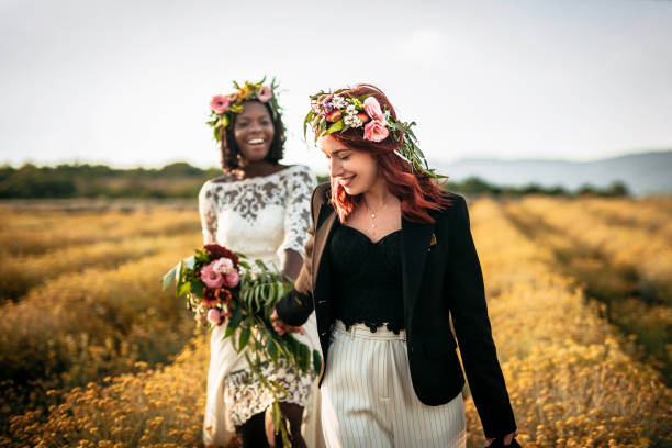 istock Two lesbian brides walking in the flower field 1164146148