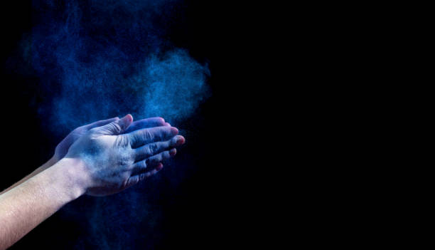 istock Hands clapping with blue holi powder on black 1164147666