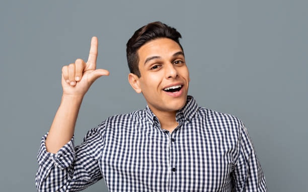 istock Handsome guy pointing finger upwards on gray background. 1164148668