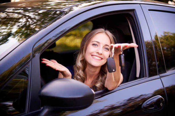 istock Happy young woman with keys in auto. 1164154372