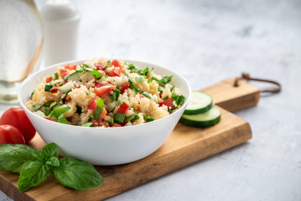 Tabbouleh - Arabian vegetarian salad Tabbouleh - Arabian vegetarian salad made of couscous, tomatoes, cucumbers, parsley, onions and lemon juice. Couscous with vegetables in a white bowl on the table. couscous stock pictures, royalty-free photos & images