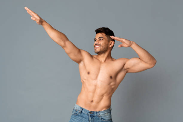 muscular topless arab man doing dab dance gesture on gray background - motion art naked studio shot imagens e fotografias de stock