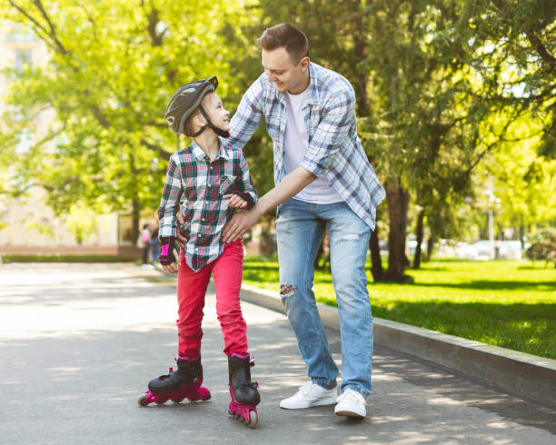 istock Happy girl in helmet learning skating with her father 1164158920