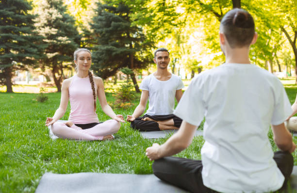 istock Yoga teacher and beginners in outdoor class, making easy postures 1164159253