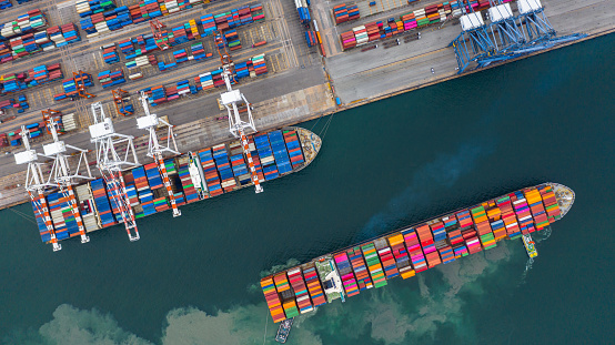 Group of diverse male container yard worker working and checking container boxes at commercial dock site. Black male and Asian male people worker inspecting container boxes from cargo freight ship