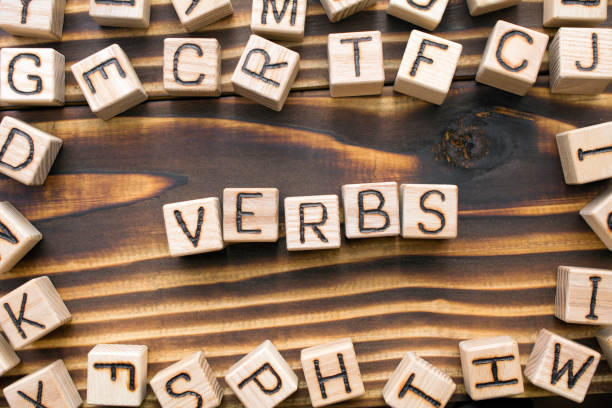 word verbs composed of wooden cubes with letters word verbs composed of wooden cubes with letters, Part of speech concept scattered around the cubes random letters, top view on wooden background verb stock pictures, royalty-free photos & images