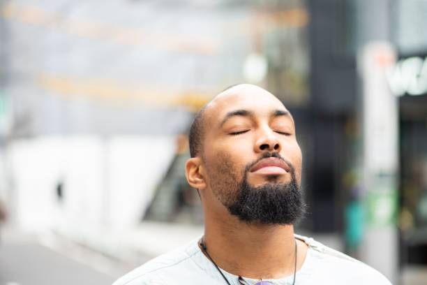 A moment of serenity A handsome man standing outside with his eyes closed, enjoying a moment of peace. eyes closed stock pictures, royalty-free photos & images
