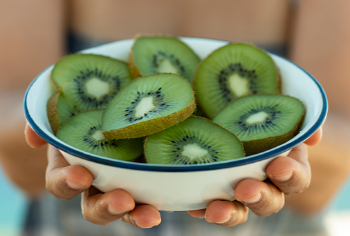 Whole and cut fresh kiwis on wooden table, closeup. Space for text