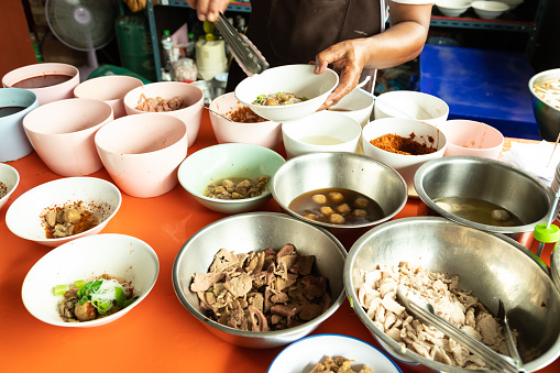 Merchant preparing noodle bowls for customers on lunch.