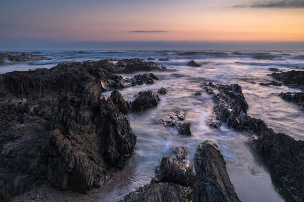 Croyde Bay seascape at sunset in North Devon, UK Waves crash over the rocks at Croyde Bay in North Devon, UK on a summer's evening at sunset. croyde bay photos stock pictures, royalty-free photos & images