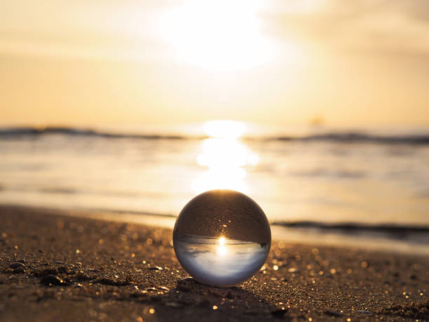 lens ball con riflesso dell'alba dorata sulla spiaggia estiva. - sunrise sun gold sea foto e immagini stock