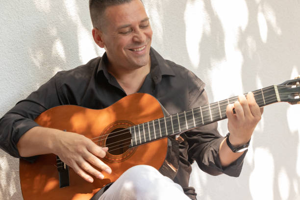 istock A handsome Spanish man, musician playing guitar and smiling because  he is happy. 1164165206