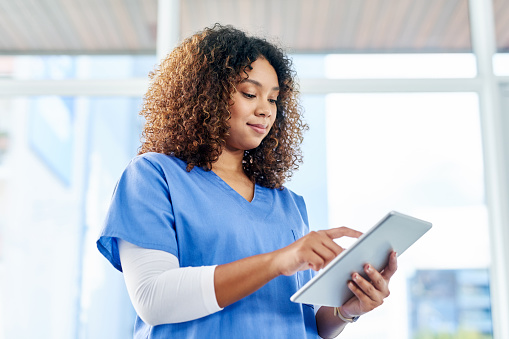 Shot of an attractive young female nurse using a digital tablet while working at a hospital