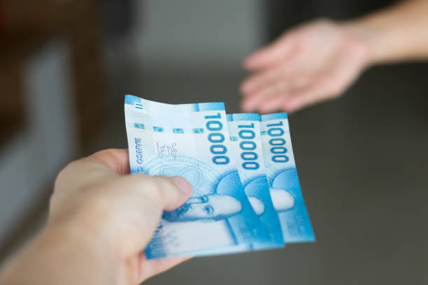 Chilean money. High resolution image. Hands giving and receiving chilean money notes. Chile ten thousand (10000) pesos. Selective focus. colombian peso stock pictures, royalty-free photos & images