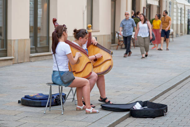 Krakow, Poland - June 06 2019: Two young women playing banduras in a touristic street. A bandura (Ukrainian: банду́ра) is a Ukrainian, plucked string, folk instrument. It combines elements of the zither and lute and, up until the 1940s, was also often referred to by the term kobza.